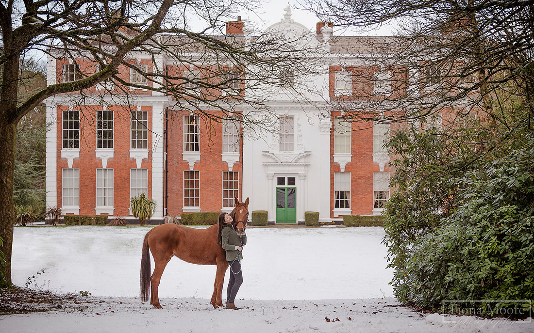 Portrait of girl and her chestnut mare outside Hilton Hall in Winter. Photograph taken by West Midlands Based Specialist Equine Photographer Fiona Moore Photography
